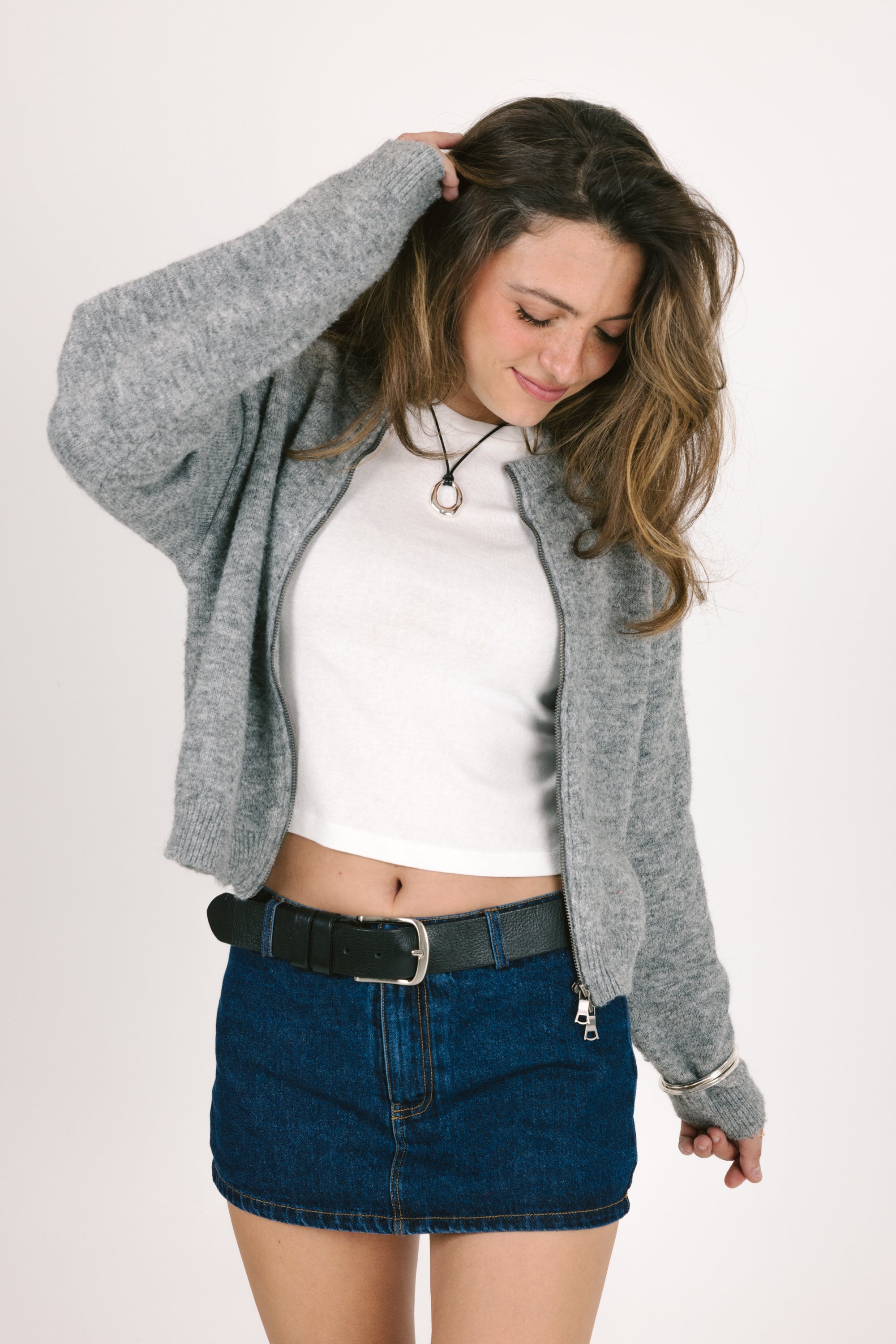 Woman wearing a gray cropped jacket and blue denim shorts on a white background